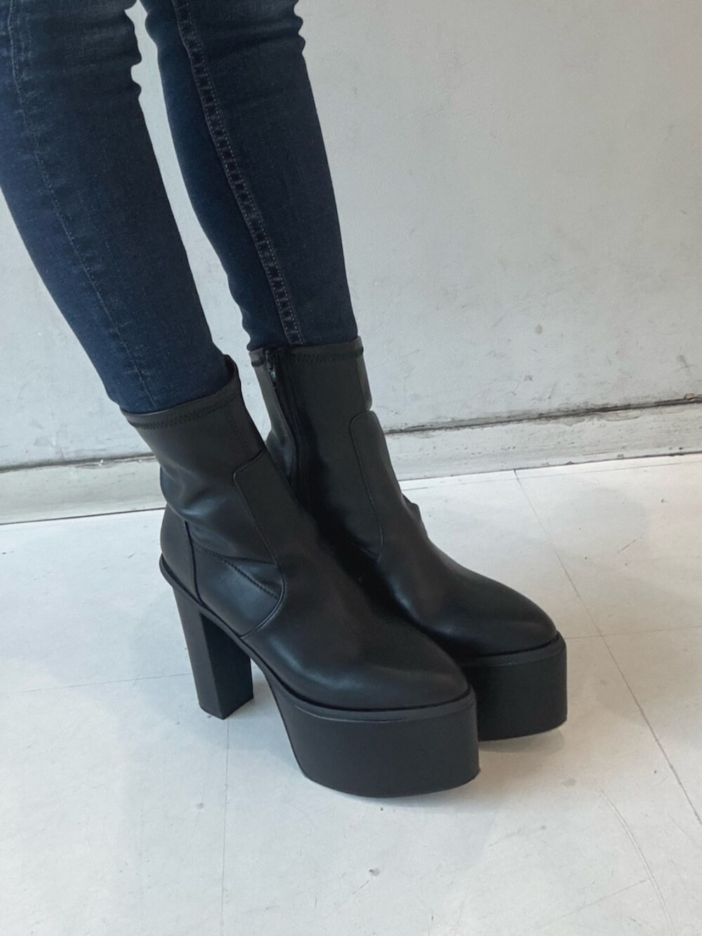 ブラック系のブーツ、ホワイト系のニット/セーター、ブルー系のデニムパンツを着用したレディースの冬コーディネートの5枚目の写真