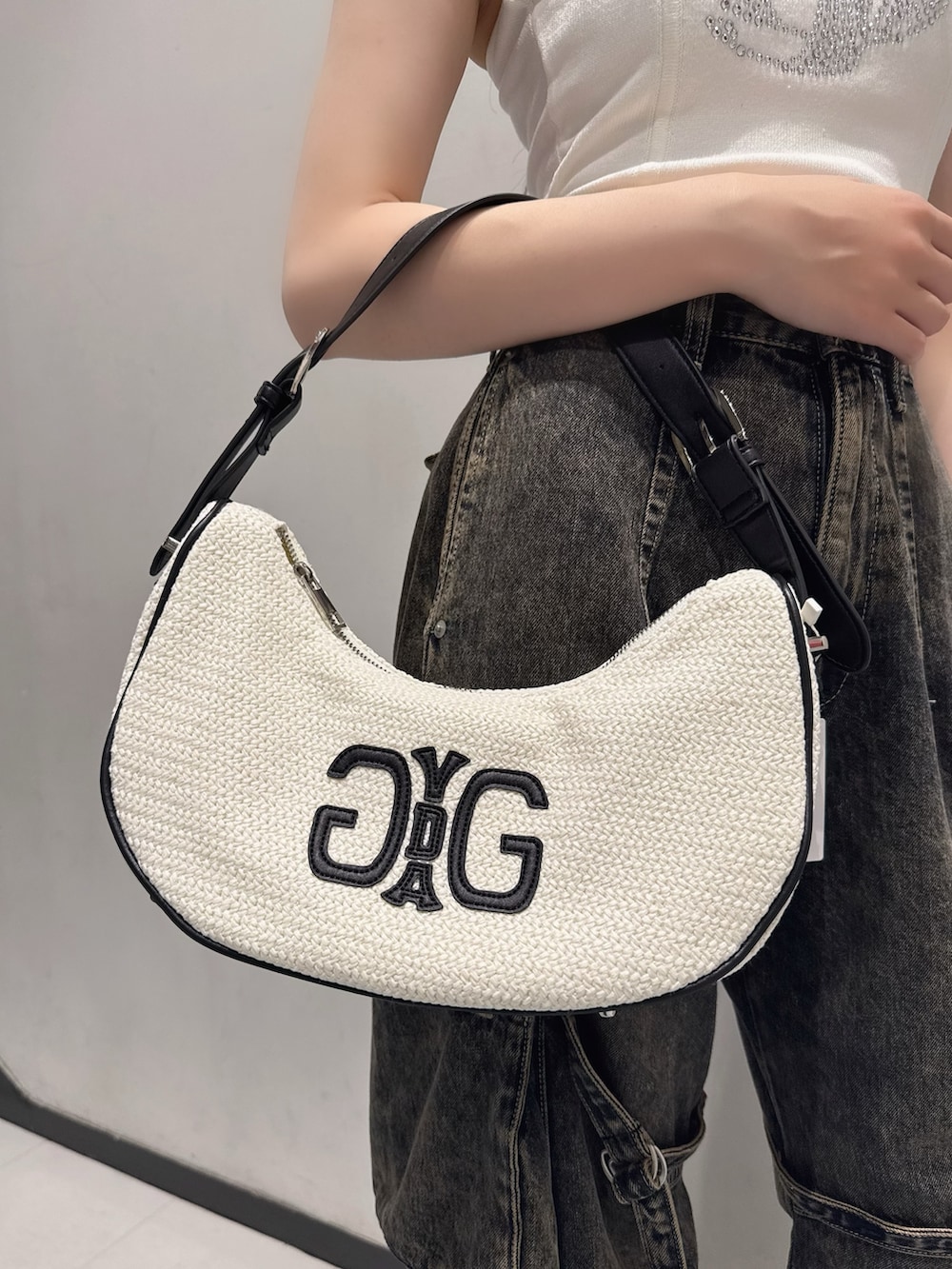 ホワイト系のキャミソール、ブルー系のデニムパンツ、ホワイト系のハンドバッグを着用したレディースの夏コーディネートの6枚目の写真