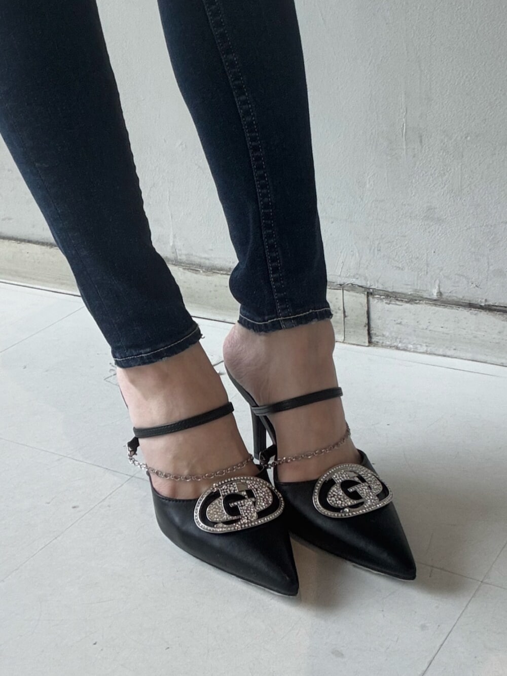 ブラック系のパンプス、ブラック系のニット/セーター、ブルー系のデニムパンツを着用したレディースの春コーディネートの6枚目の写真