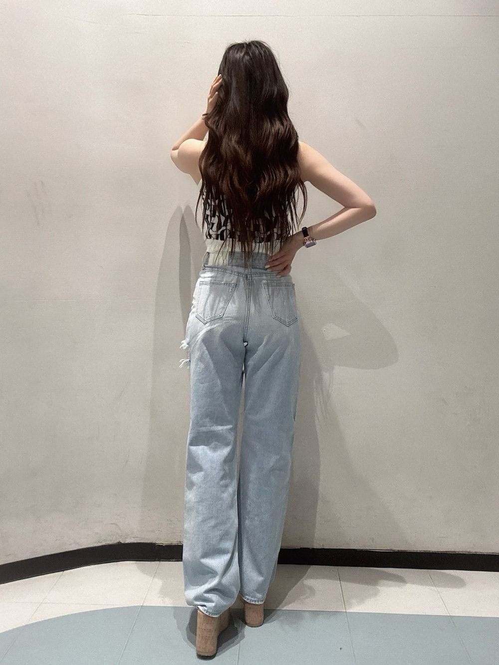 ブルー系のデニムパンツ、ホワイト系のニット/セーター、ホワイト系のサンダルを着用したレディースの春コーディネートの3枚目の写真