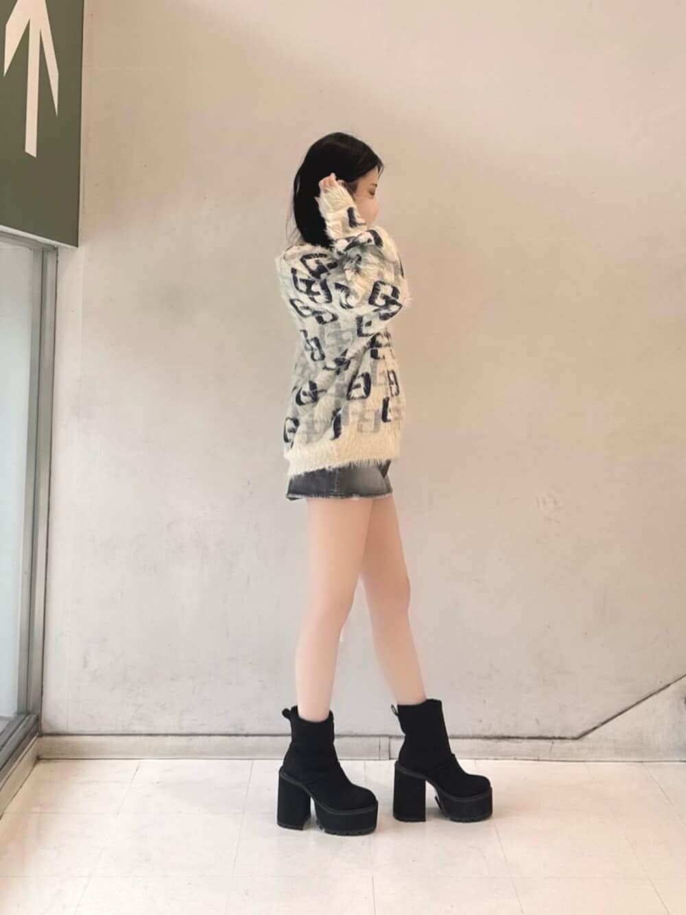 ブラック系のデニムスカート、ホワイト系のニット/セーター、ブラック系のブーツを着用したレディースの冬コーディネートの2枚目の写真