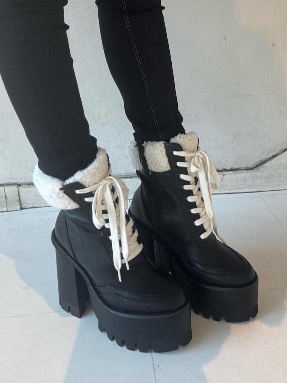 ブラック系のブーツ、ホワイト系のニット/セーター、ブラック系のムートンコートを着用したレディースの冬コーディネートの5枚目の写真