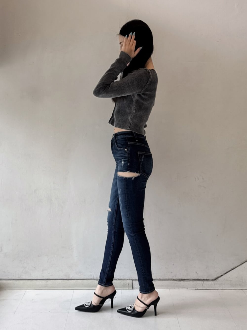 ブラック系のパンプス、ブラック系のニット/セーター、ブルー系のデニムパンツを着用したレディースの春コーディネートの2枚目の写真