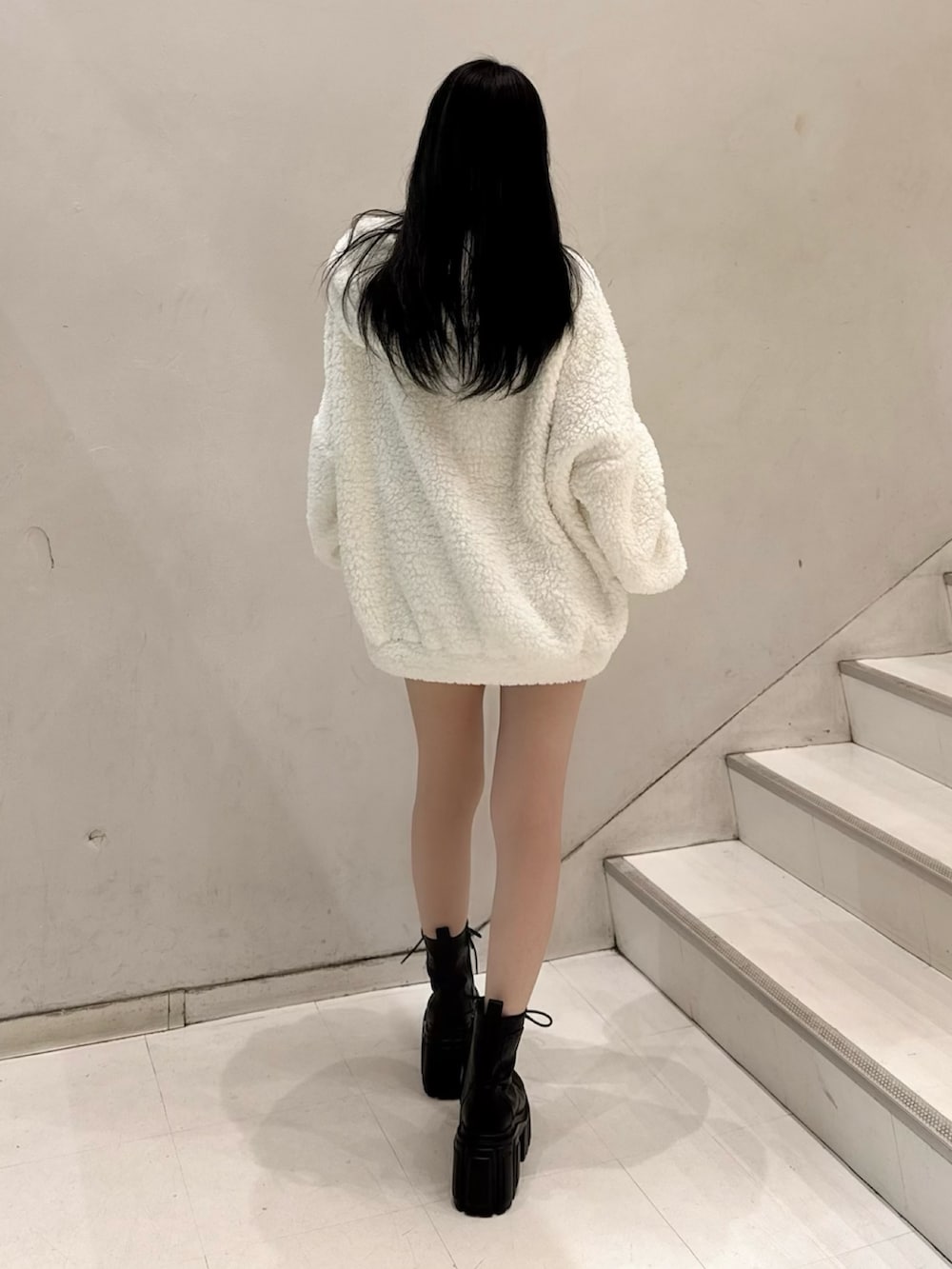 ホワイト系のパーカー、ブラック系のスカート、ブラック系のブーツを着用したレディースの秋コーディネートの3枚目の写真