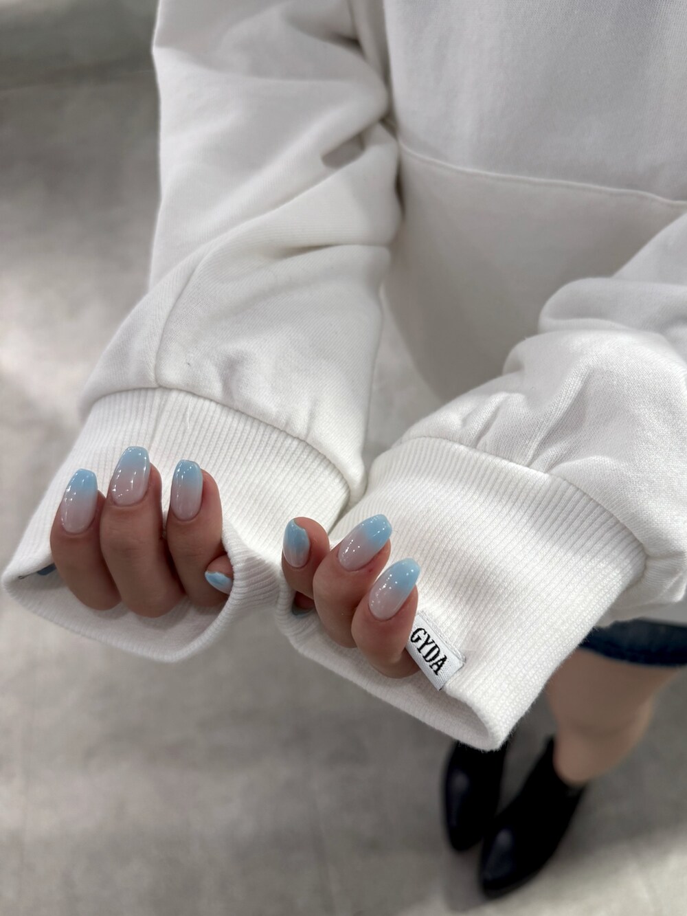 ホワイト系のパーカー、ブラック系のデニムスカート、ブラック系のブーツを着用したレディースの冬コーディネートの5枚目の写真