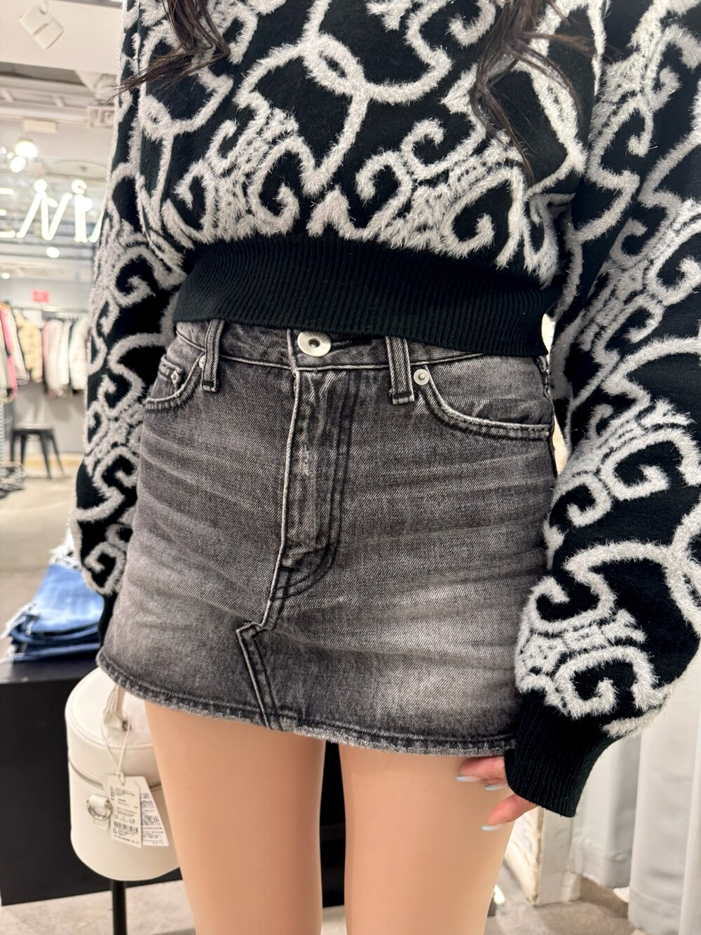 ブラック系のニット/セーター、ブラック系のデニムスカート、ホワイト系のハンドバッグを着用したレディースの冬コーディネートの5枚目の写真