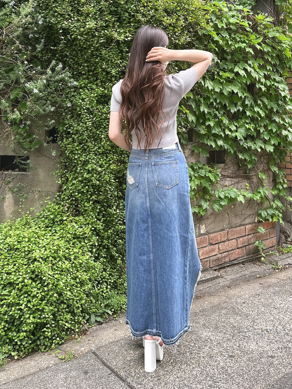 シルバー系のニット/セーター、ブルー系のデニムスカート、ホワイト系のサンダルを着用したレディースの春コーディネートの2枚目の写真