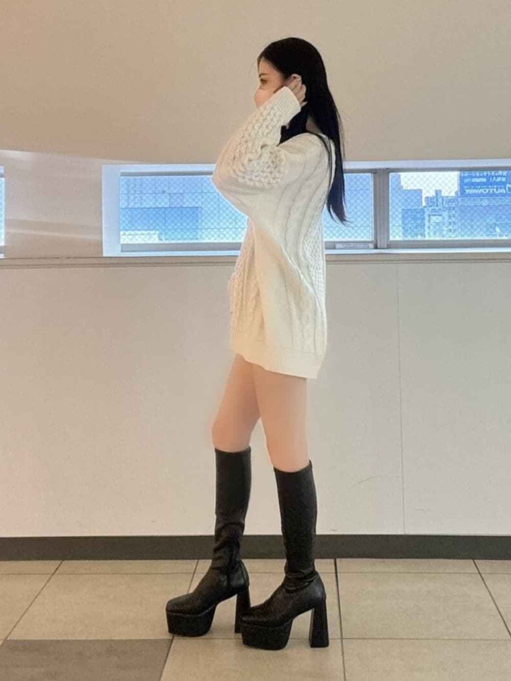 ブラック系のブーツ、ブラック系のデニムスカート、ホワイト系のニット/セーターを着用したレディースの冬コーディネートの3枚目の写真