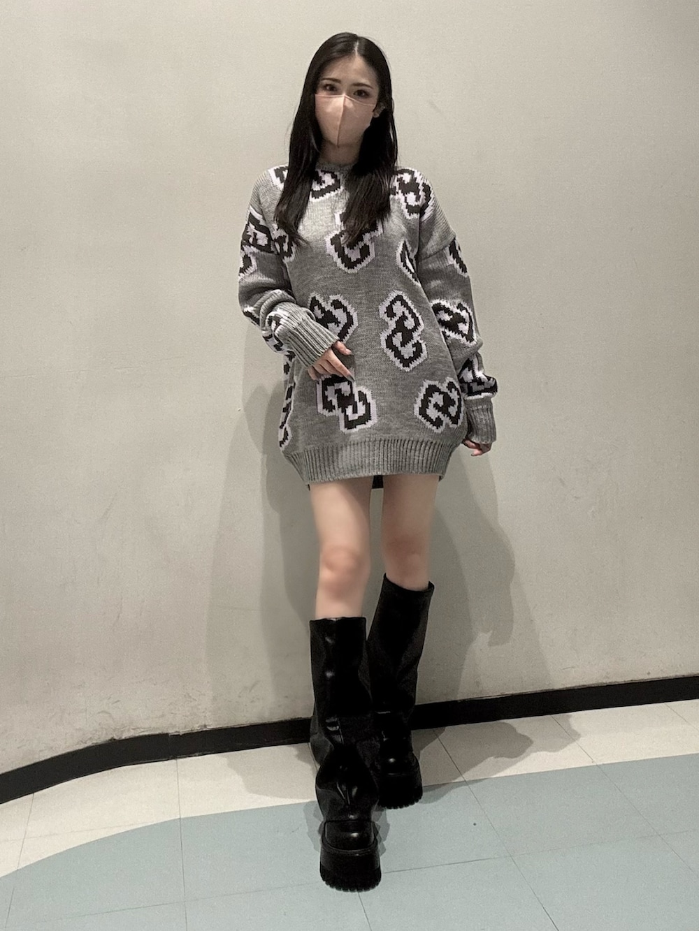 グレー系のニット/セーター、ブラック系のスカート、ブラック系のブーツを着用したレディースの秋コーディネートの2枚目の写真