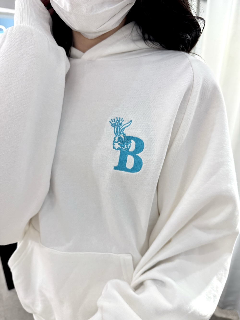 ホワイト系のパーカー、ブラック系のデニムスカート、ブラック系のブーツを着用したレディースの冬コーディネートの4枚目の写真