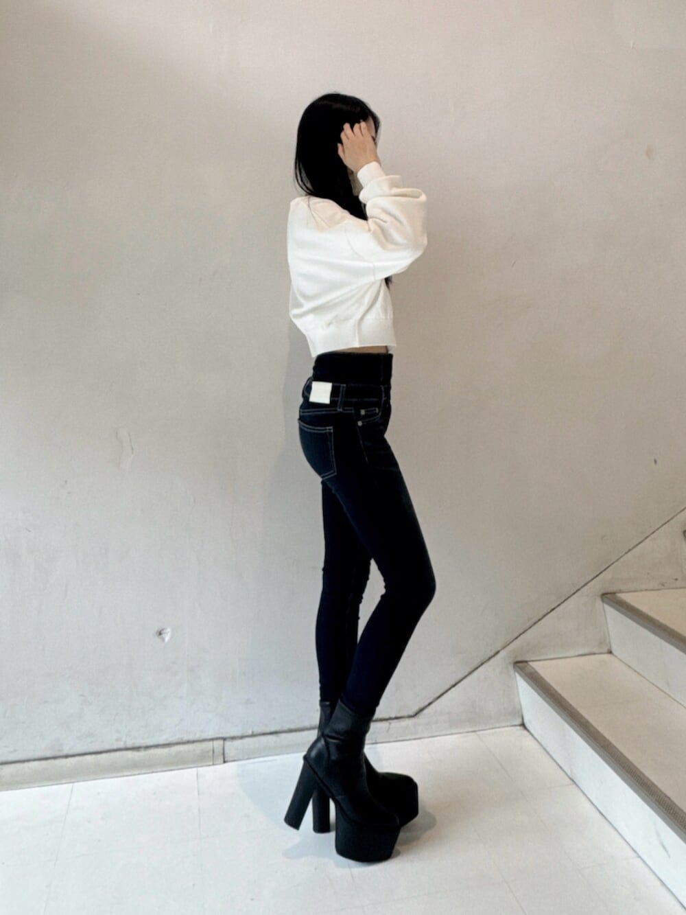 ブラック系のブーツ、ブルー系のデニムパンツ、ホワイト系のニット/セーターを着用したレディースの秋コーディネートの2枚目の写真