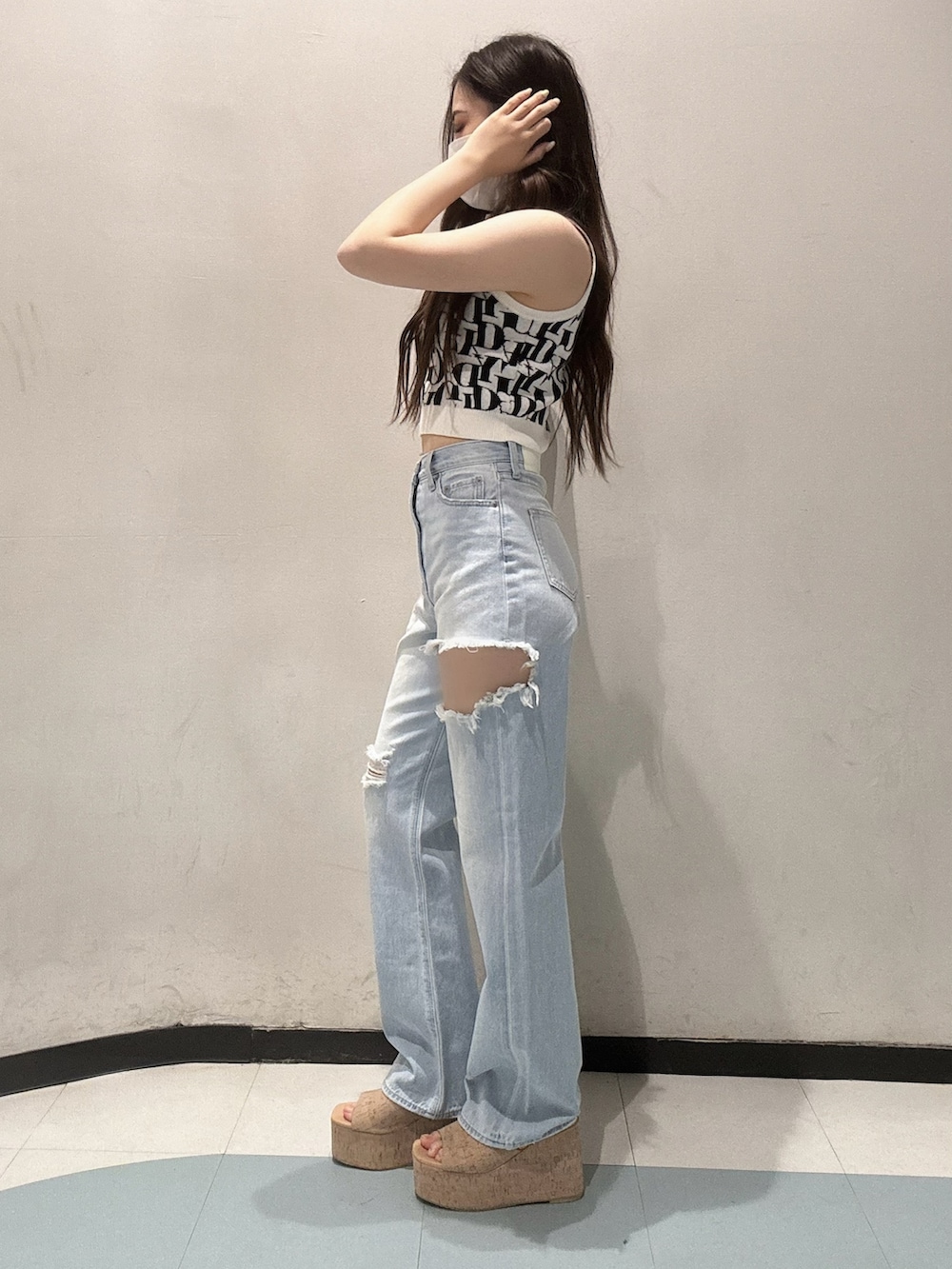 ブルー系のデニムパンツ、ホワイト系のニット/セーター、ホワイト系のサンダルを着用したレディースの春コーディネートの2枚目の写真