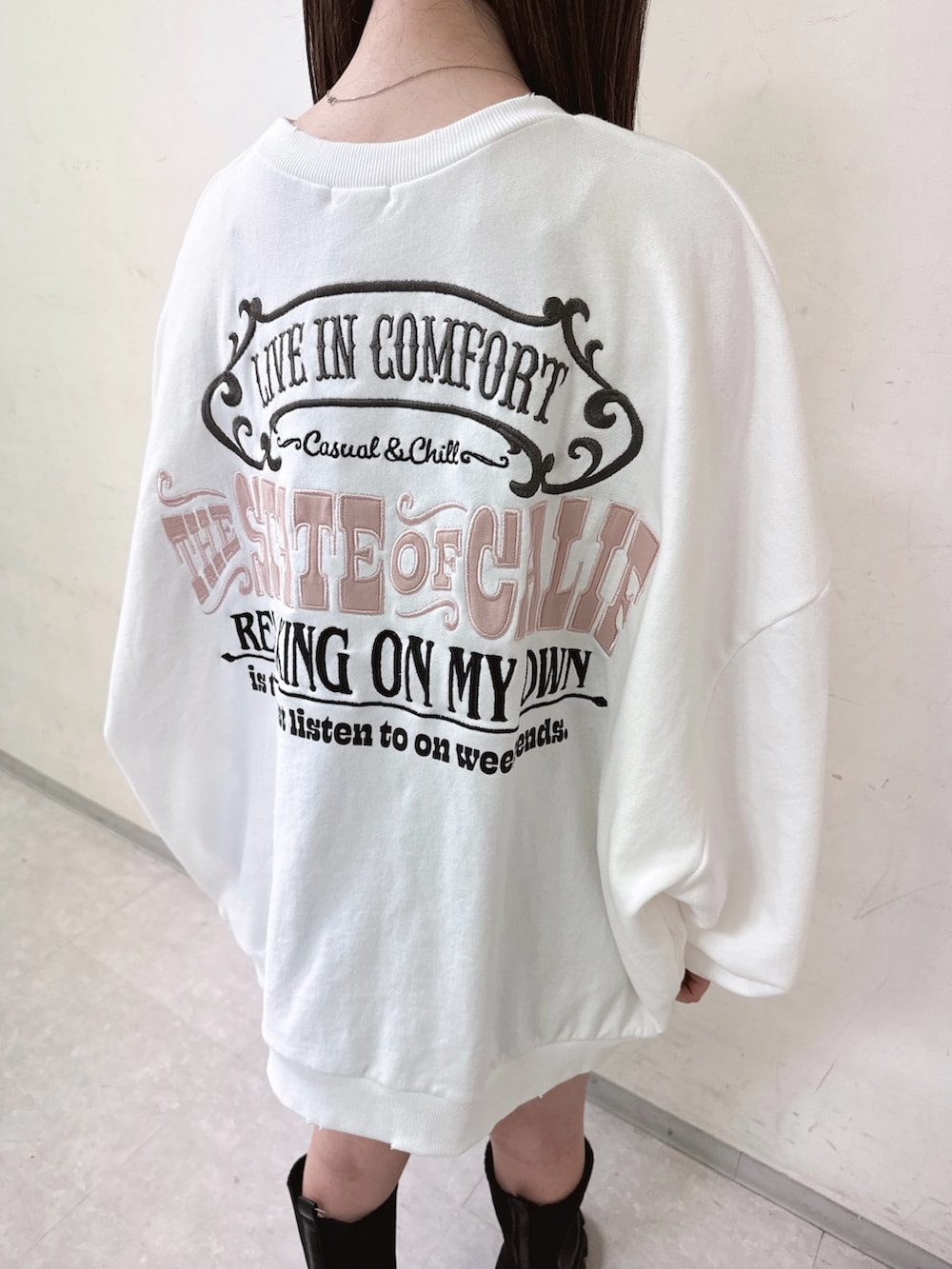 ホワイト系のスウェット、ブラック系のデニムスカート、ブラック系のブーツを着用したレディースの秋コーディネートの5枚目の写真