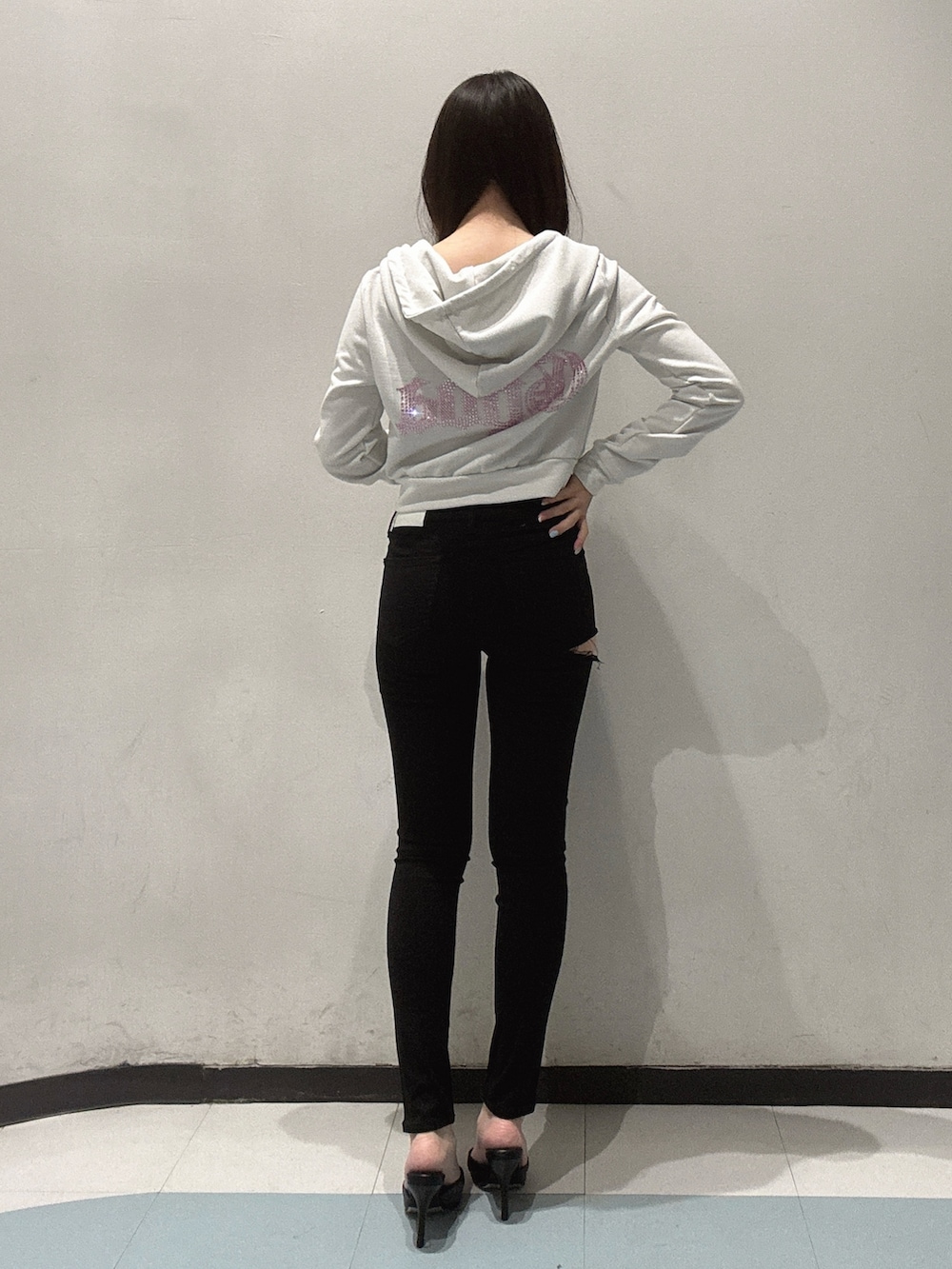 ホワイト系のパーカー、ブラック系のキャミソール、ブラック系のデニムパンツを着用したレディースの春コーディネートの3枚目の写真