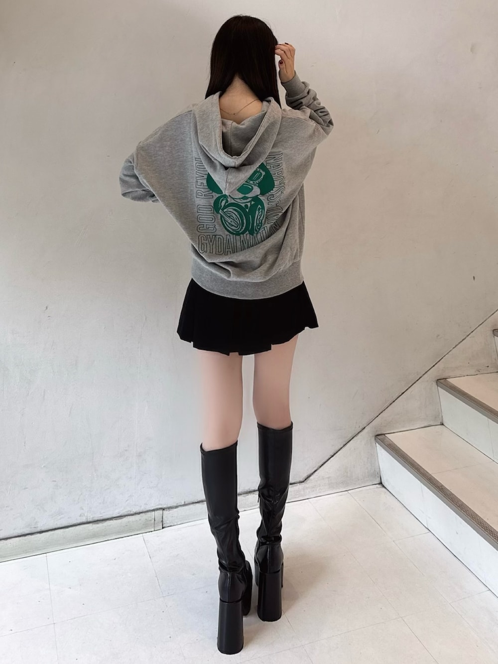 グレー系のパーカー、ブラック系のスカート、ブラック系のブーツを着用したレディースの冬コーディネートの2枚目の写真