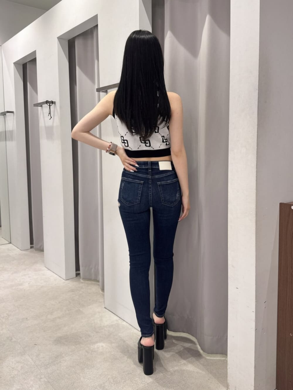 ホワイト系のタンクトップ、ブルー系のデニムパンツ、ブラック系のサンダルを着用したレディースの夏コーディネートの3枚目の写真