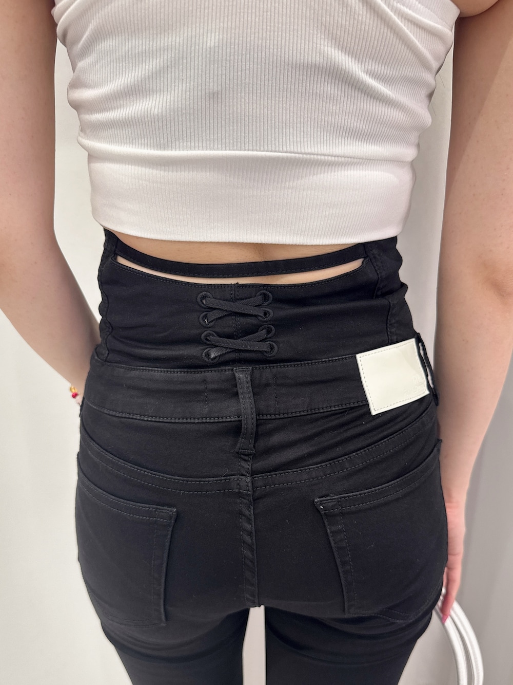 ホワイト系のタンクトップ、ブラック系のデニムパンツ、ブラック系のサンダルを着用したレディースの夏コーディネートの5枚目の写真