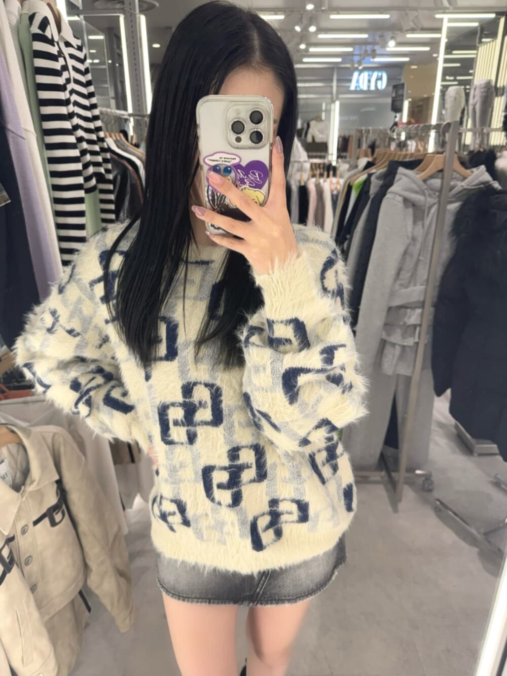 ブラック系のデニムスカート、ホワイト系のニット/セーター、ブラック系のブーツを着用したレディースの冬コーディネートの4枚目の写真