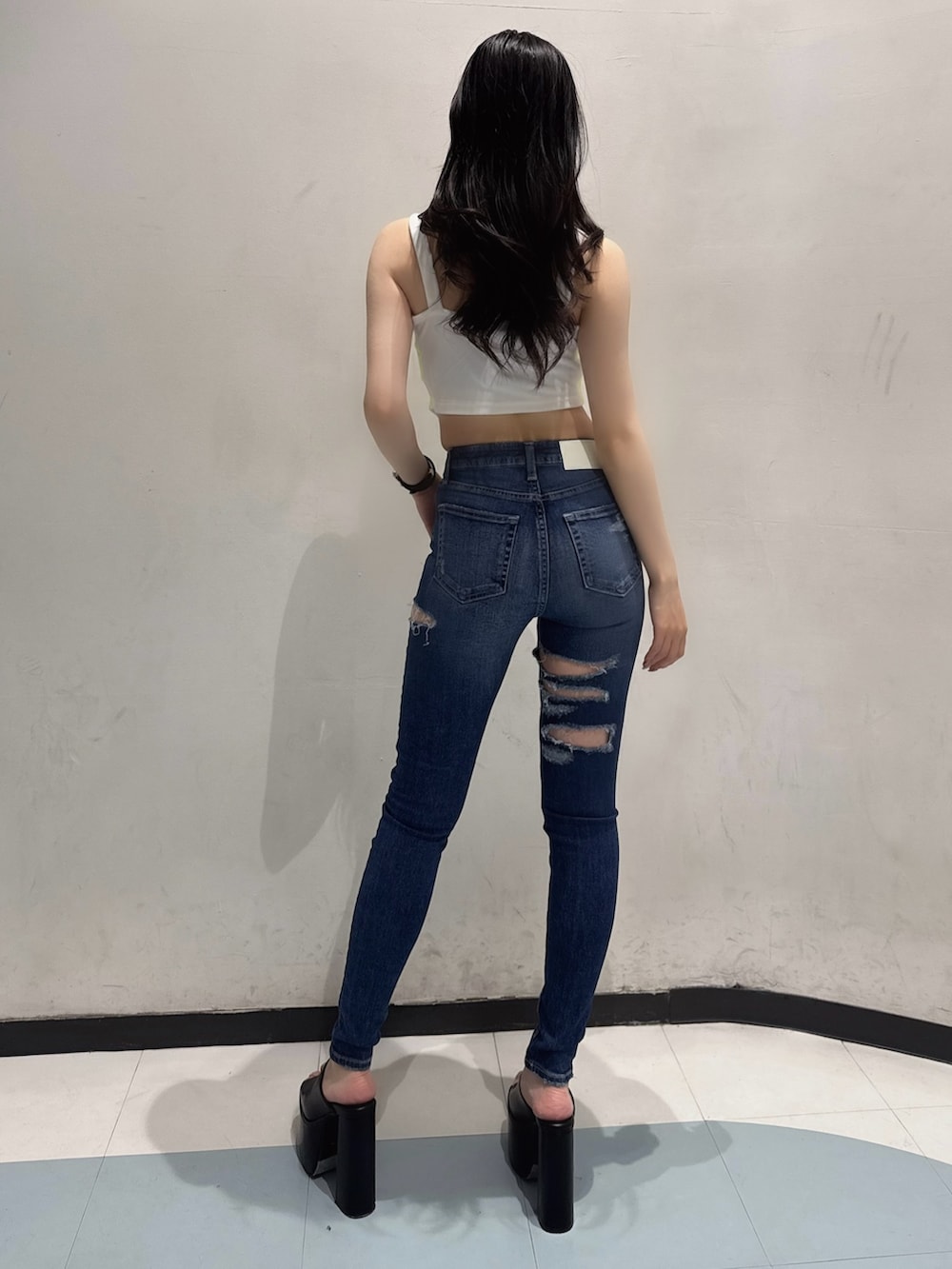 ホワイト系のキャミソール、ブルー系のデニムパンツ、ブラック系のサンダルを着用したレディースの夏コーディネートの3枚目の写真