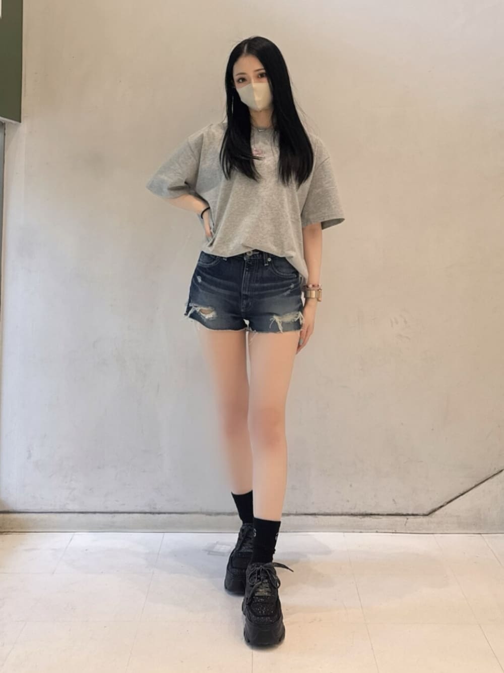グレー系のTシャツ/カットソー、ブルー系のデニムパンツ、ブラック系のスニーカーを着用したレディースの春コーディネートの2枚目の写真