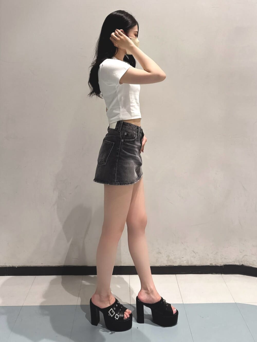 ブラック系のデニムスカート、ホワイト系のTシャツ/カットソー、ブラック系のサンダルを着用したレディースの夏コーディネートの2枚目の写真