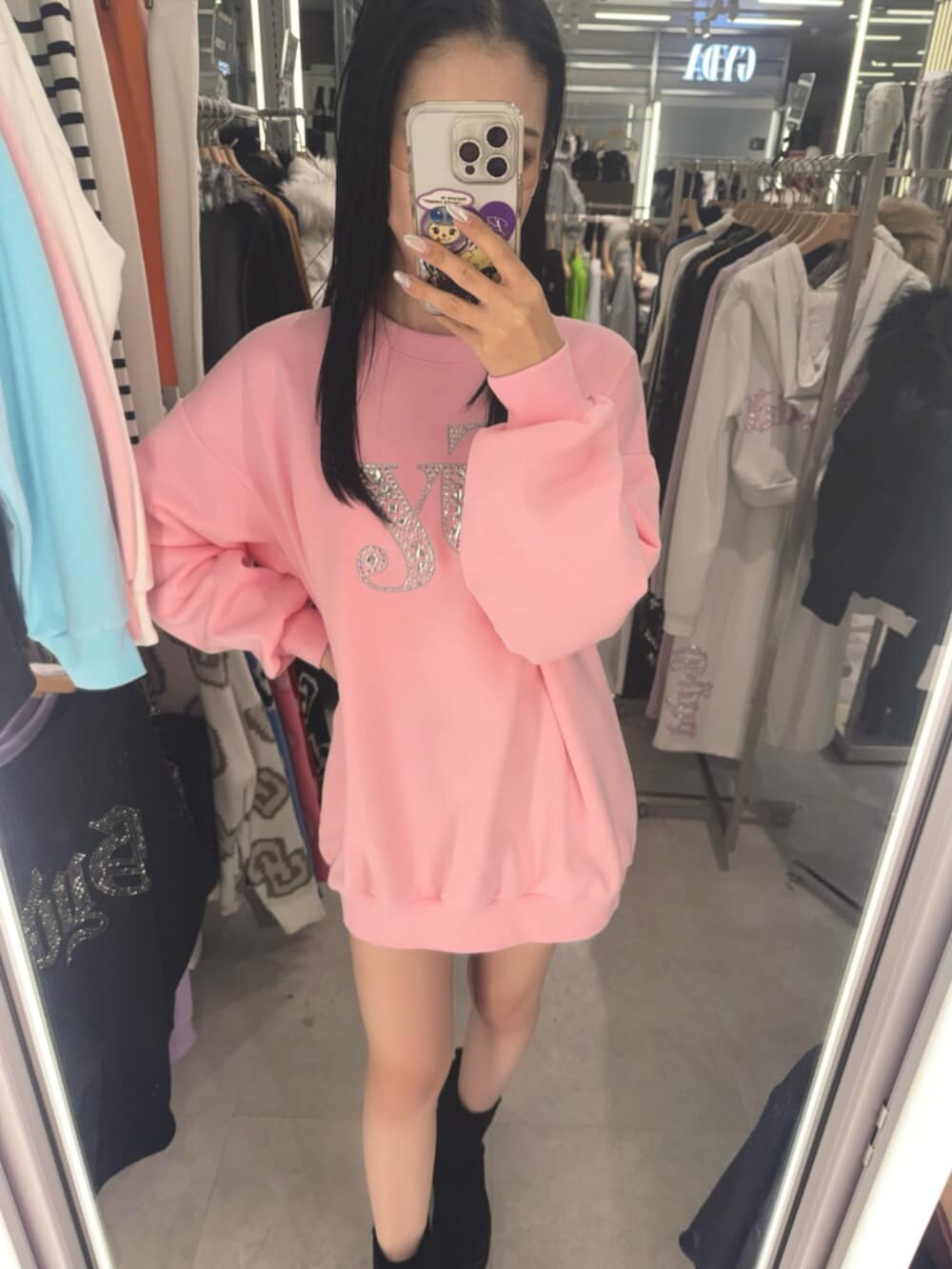 ブラック系のスカート、ブラック系のブーツ、ピンク系のスウェットを着用したレディースの冬コーディネートの4枚目の写真