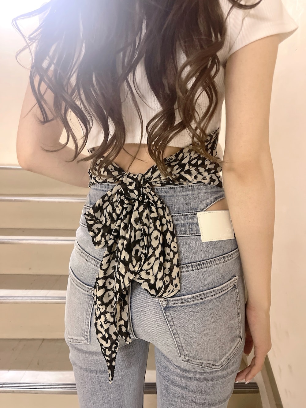 ブラック系のハンドバッグ、ブルー系のデニムパンツ、ホワイト系のTシャツ/カットソーを着用したレディースの春コーディネートの4枚目の写真