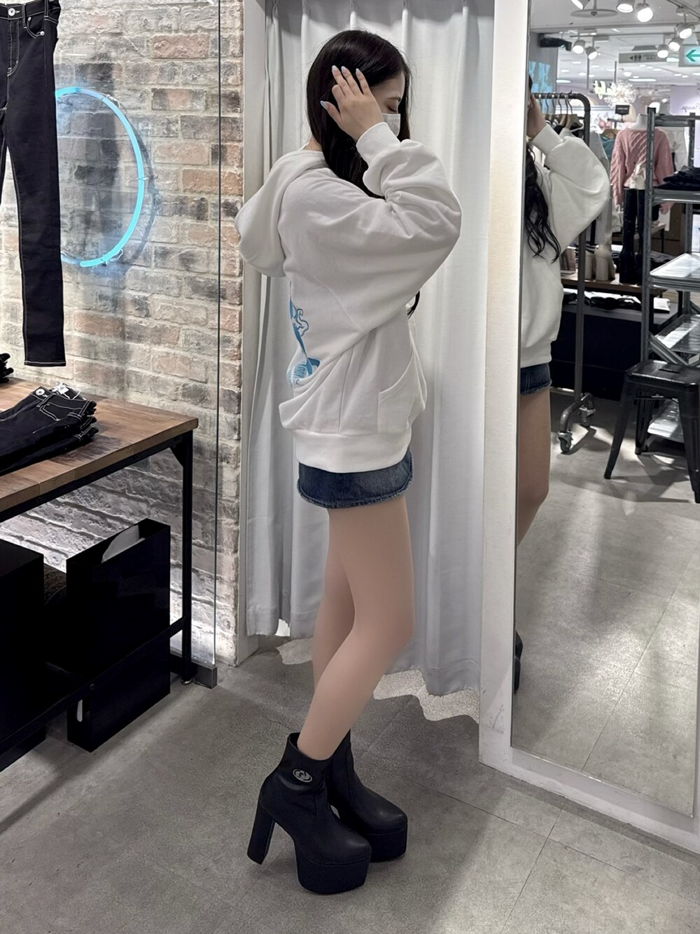 ホワイト系のパーカー、ブラック系のデニムスカート、ブラック系のブーツを着用したレディースの冬コーディネートの3枚目の写真