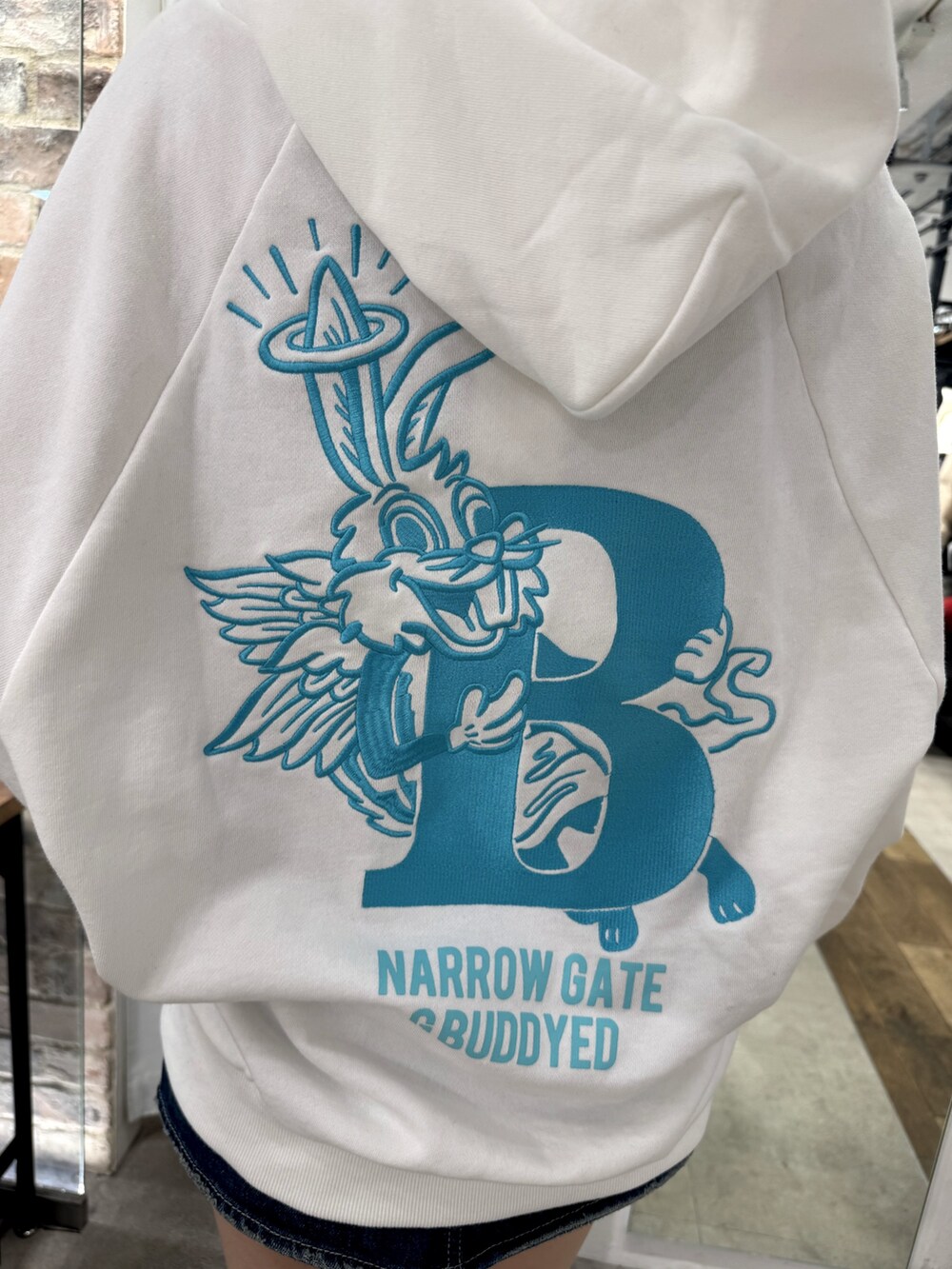 ホワイト系のパーカー、ブラック系のデニムスカート、ブラック系のブーツを着用したレディースの冬コーディネートの6枚目の写真