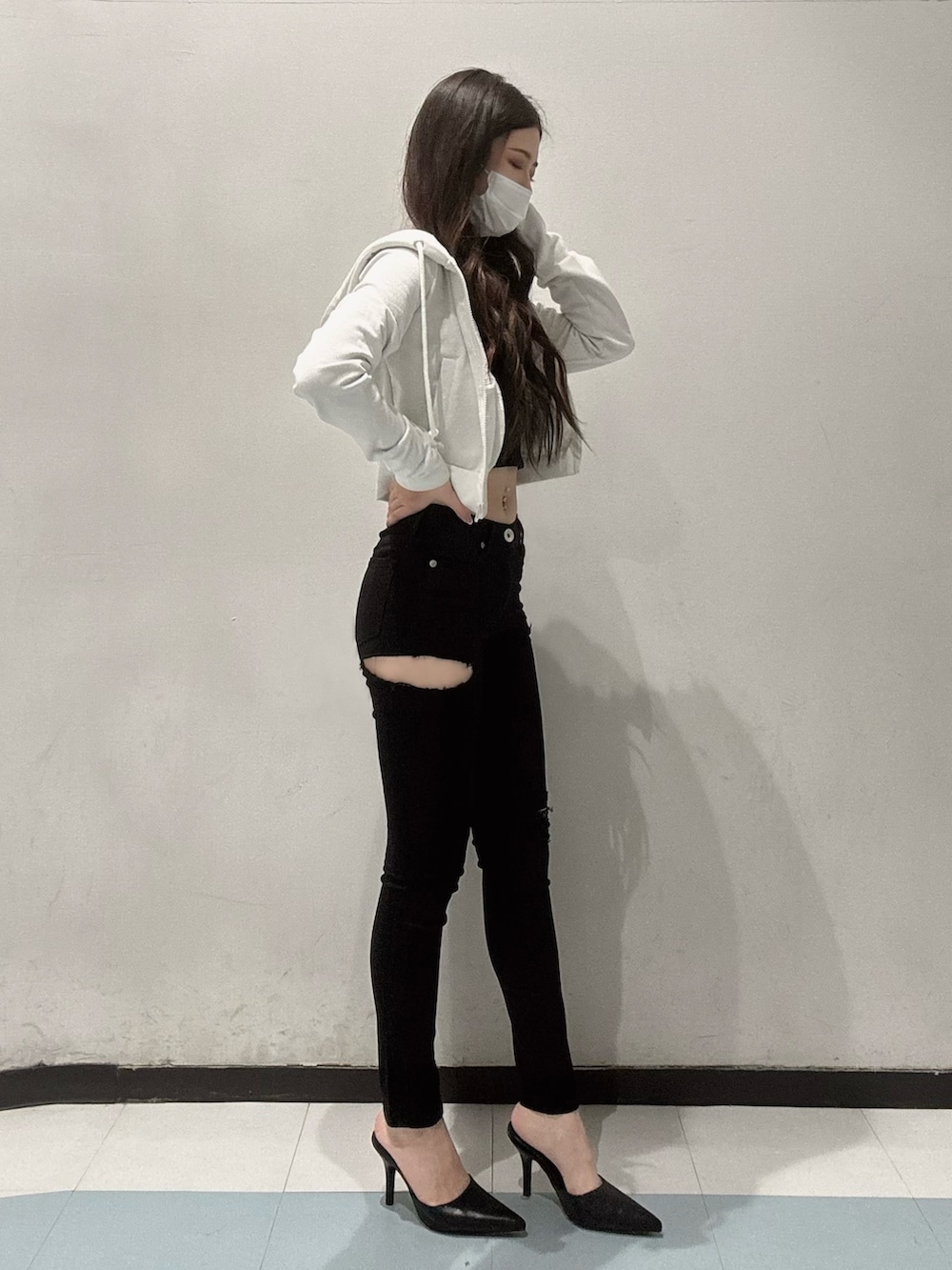 ホワイト系のパーカー、ブラック系のキャミソール、ブラック系のデニムパンツを着用したレディースの春コーディネートの2枚目の写真
