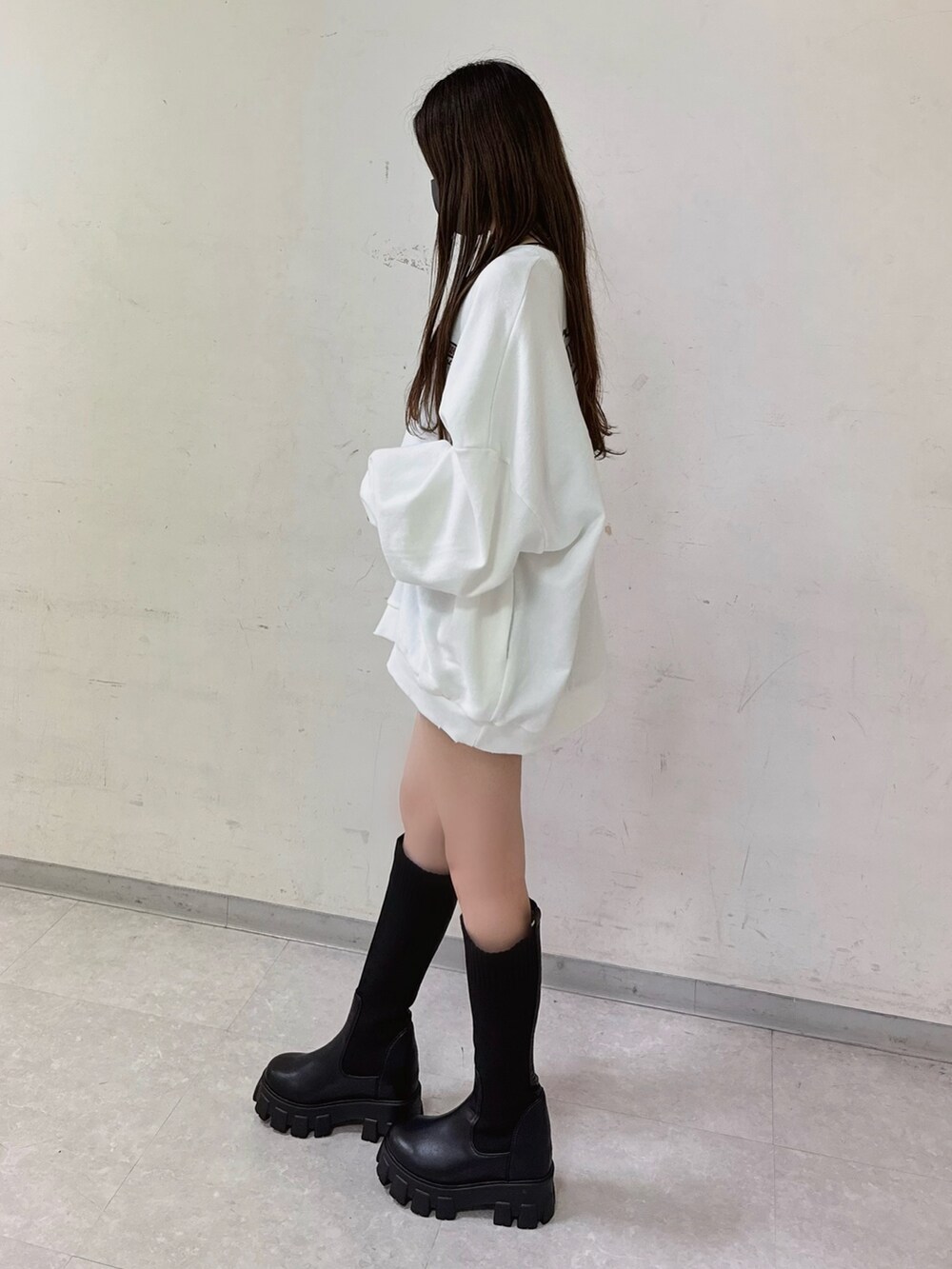 ホワイト系のスウェット、ブラック系のデニムスカート、ブラック系のブーツを着用したレディースの秋コーディネートの2枚目の写真