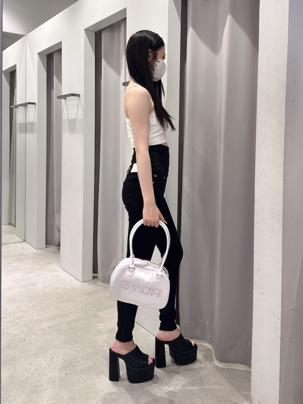 ホワイト系のタンクトップ、ブラック系のデニムパンツ、ブラック系のサンダルを着用したレディースの夏コーディネートの2枚目の写真