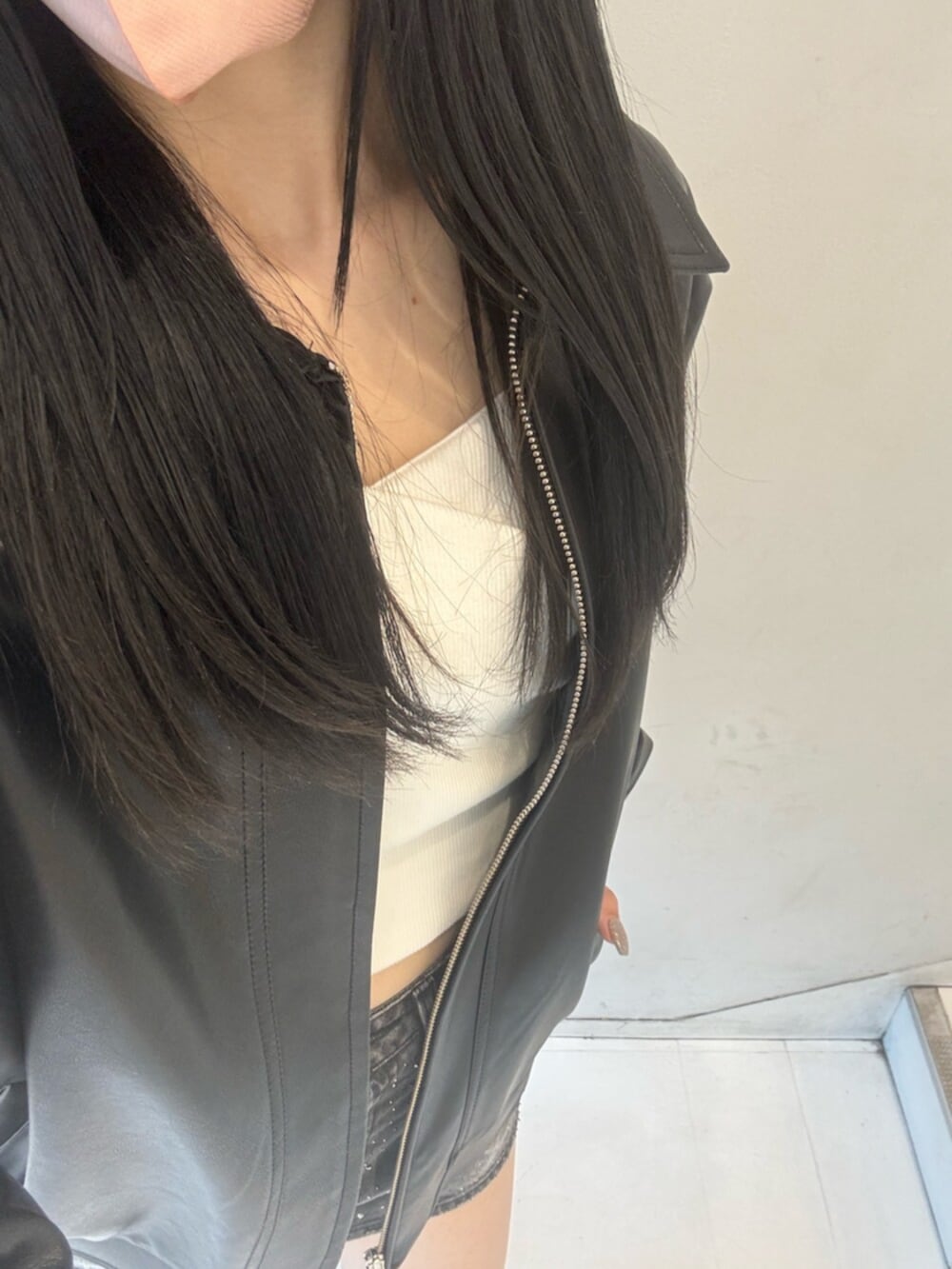 ブラック系のデニムスカート、ホワイト系のTシャツ/カットソー、ブラック系のブルゾンを着用したレディースの冬コーディネートの6枚目の写真