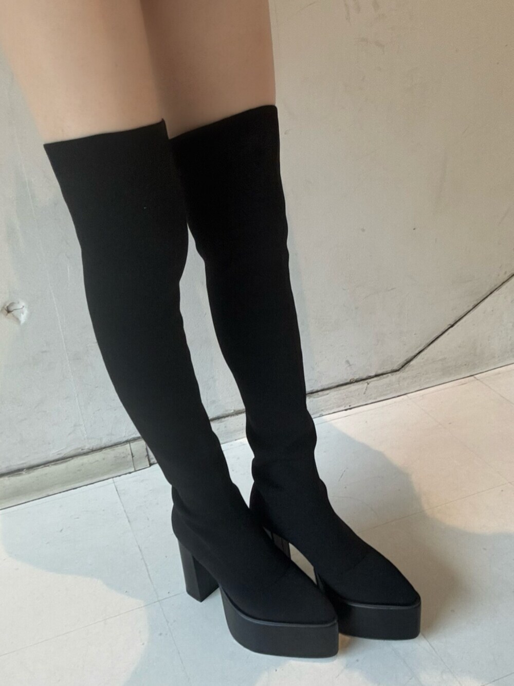 ホワイト系のニット/セーター、ブラック系のデニムスカート、ブラック系のダウンジャケット/コートを着用したレディースの秋コーディネートの8枚目の写真