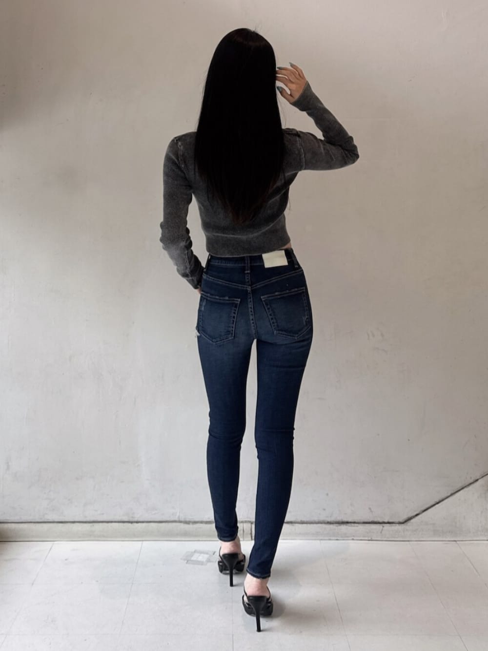 ブラック系のパンプス、ブラック系のニット/セーター、ブルー系のデニムパンツを着用したレディースの春コーディネートの3枚目の写真