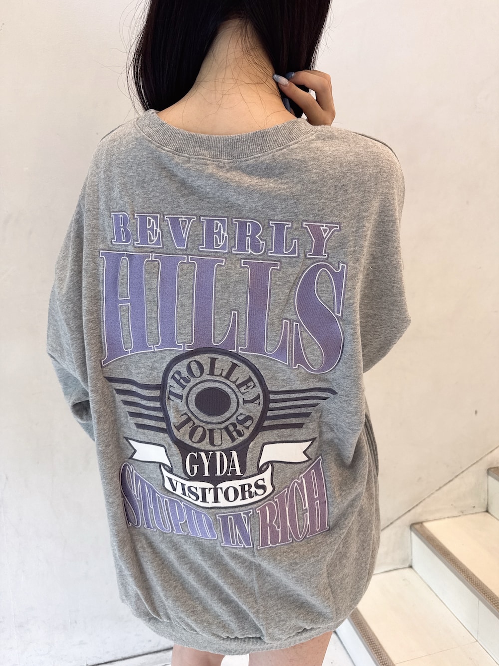 グレー系のスウェット、ブラック系のデニムスカート、ブラック系のブーツを着用したレディースの夏コーディネートの5枚目の写真