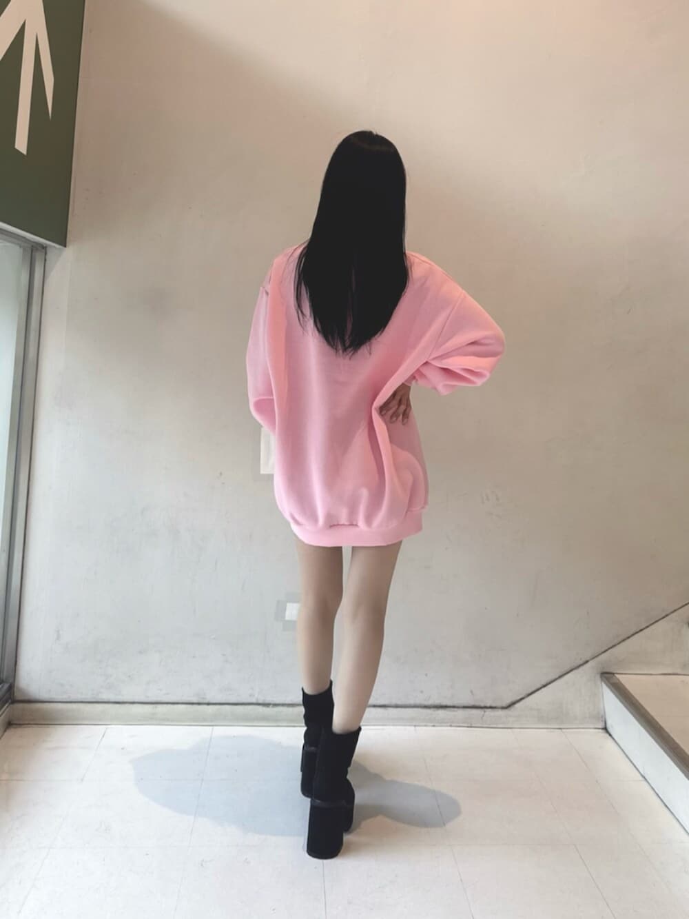 ブラック系のスカート、ブラック系のブーツ、ピンク系のスウェットを着用したレディースの冬コーディネートの3枚目の写真