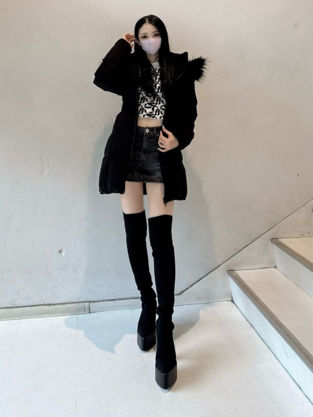 ホワイト系のニット/セーター、ブラック系のデニムスカート、ブラック系のダウンジャケット/コートを着用したレディースの秋コーディネートの4枚目の写真