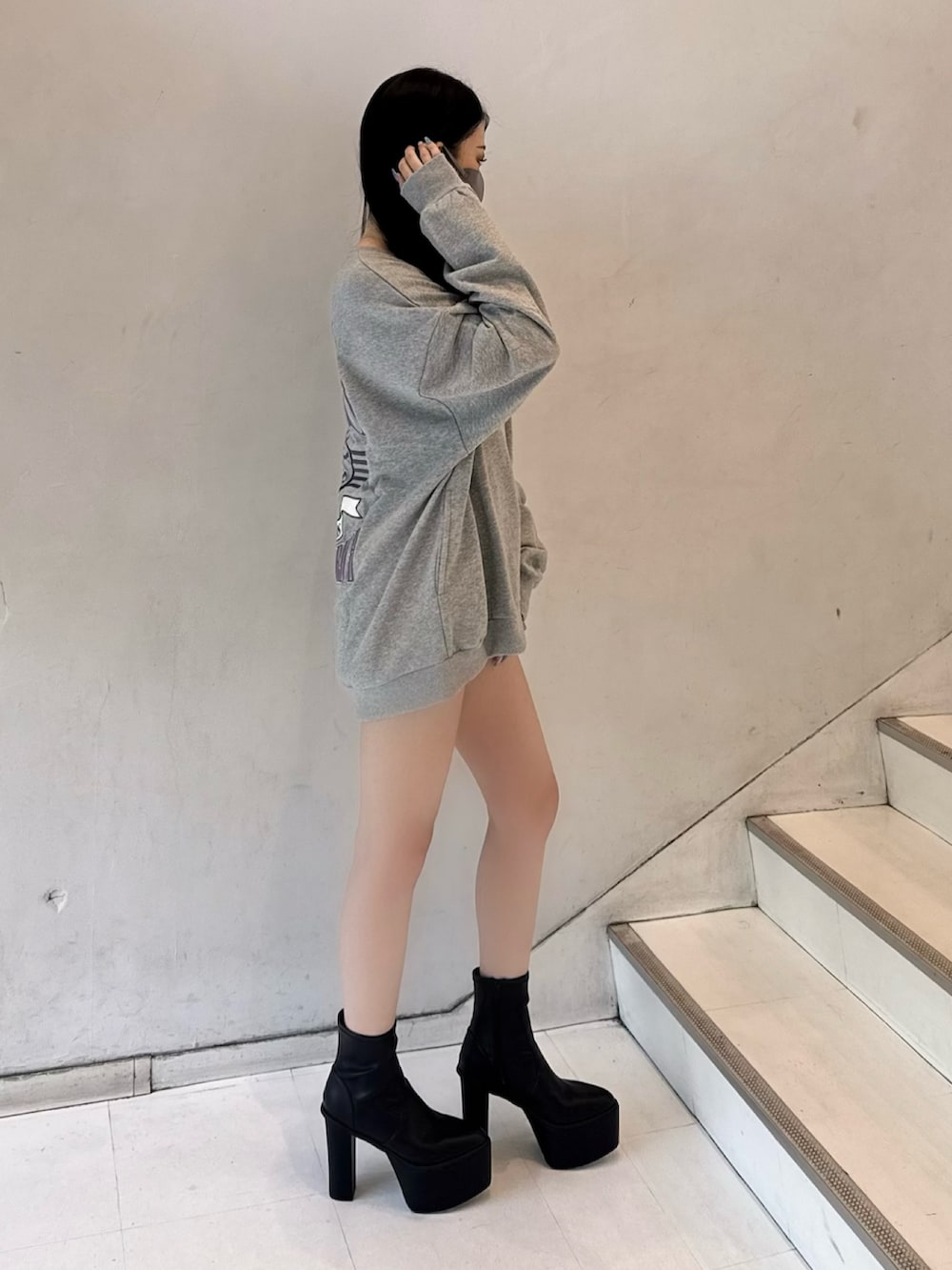 グレー系のスウェット、ブラック系のデニムスカート、ブラック系のブーツを着用したレディースの夏コーディネートの2枚目の写真