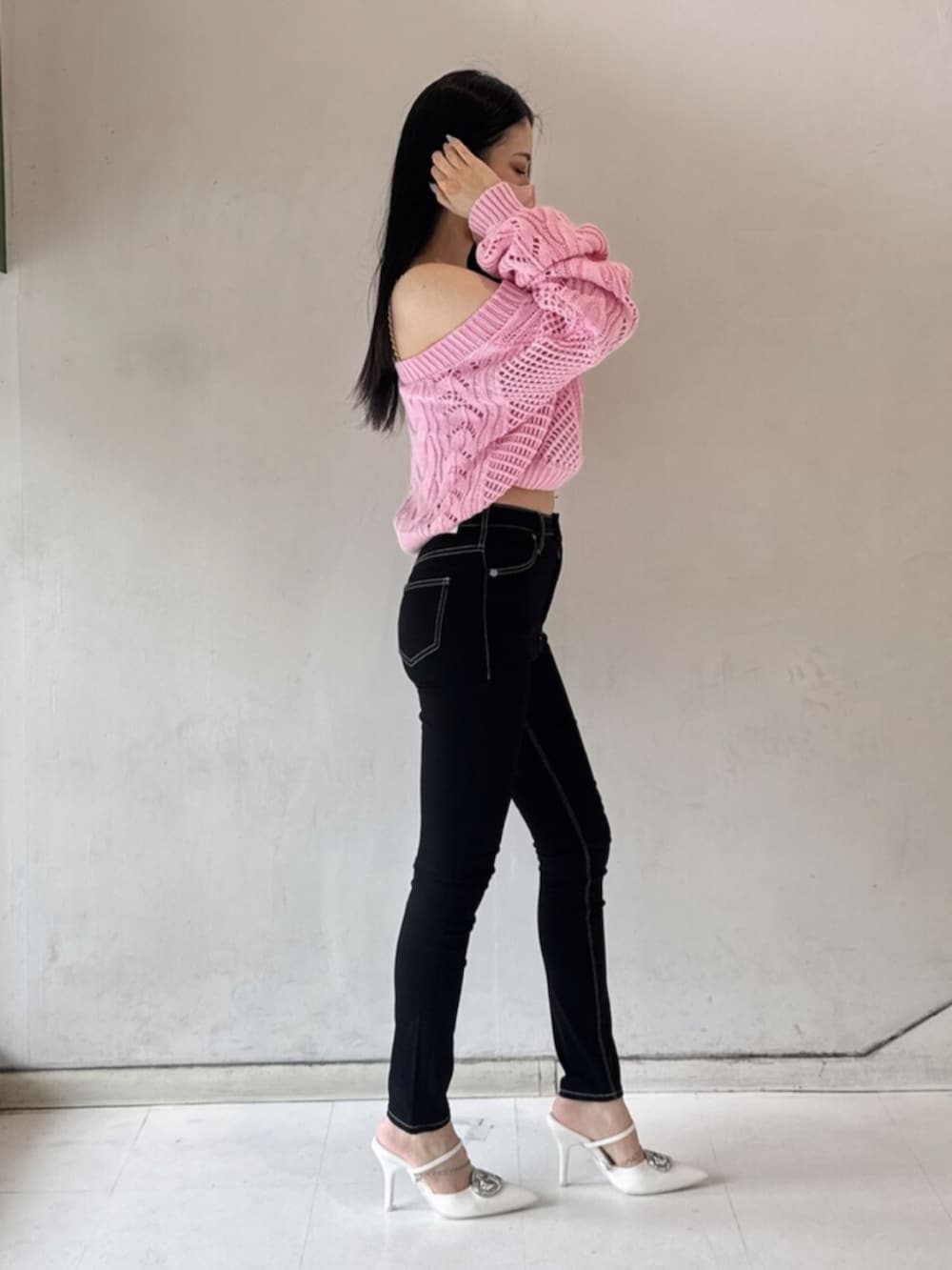 ブラック系のデニムパンツ、ホワイト系のキャミソール、ピンク系のニット/セーターを着用したレディースの春コーディネートの2枚目の写真