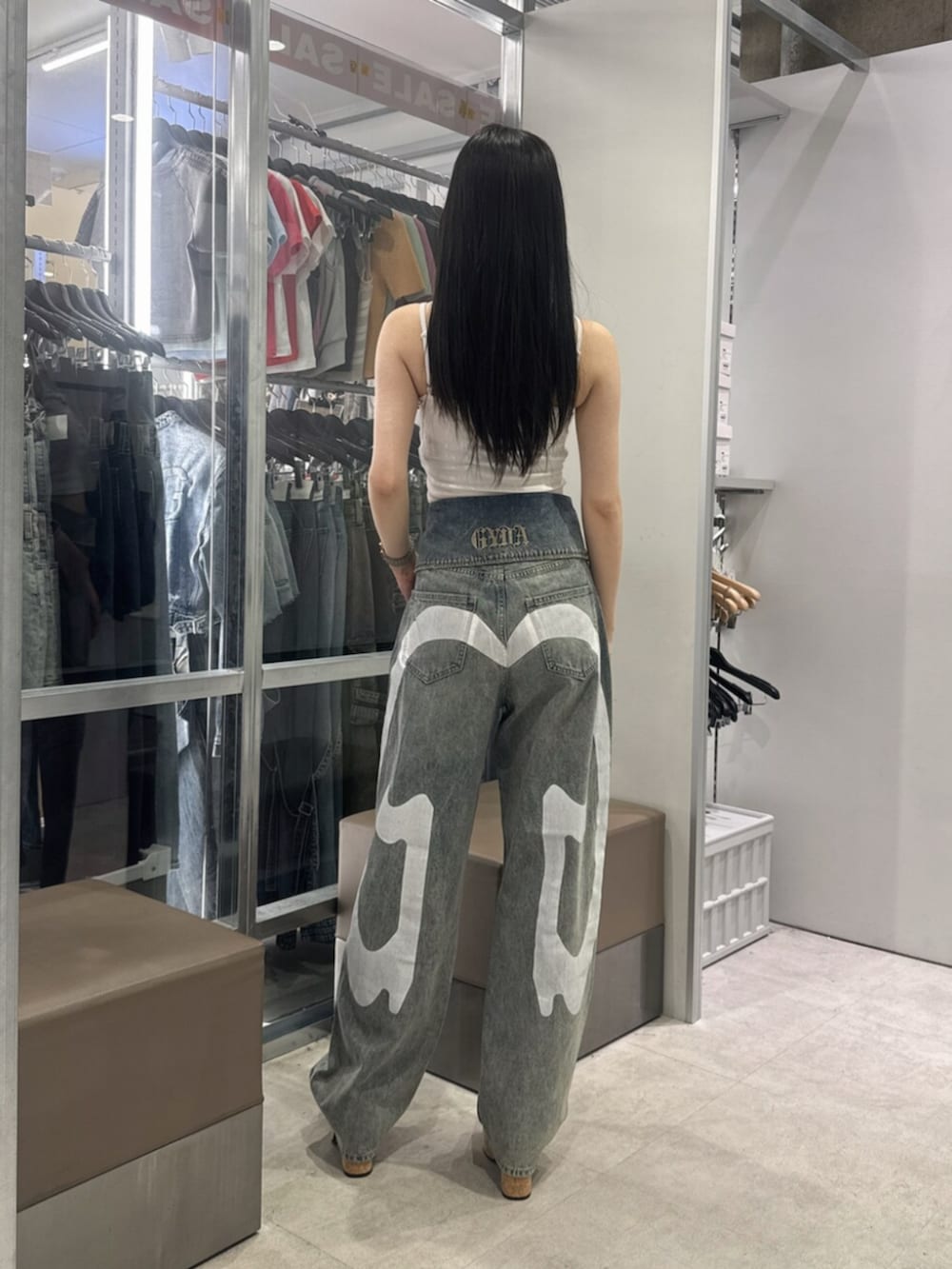 ブラック系のサンダル、ホワイト系のキャミソール、ブルー系のデニムパンツを着用したレディースの夏コーディネートの3枚目の写真