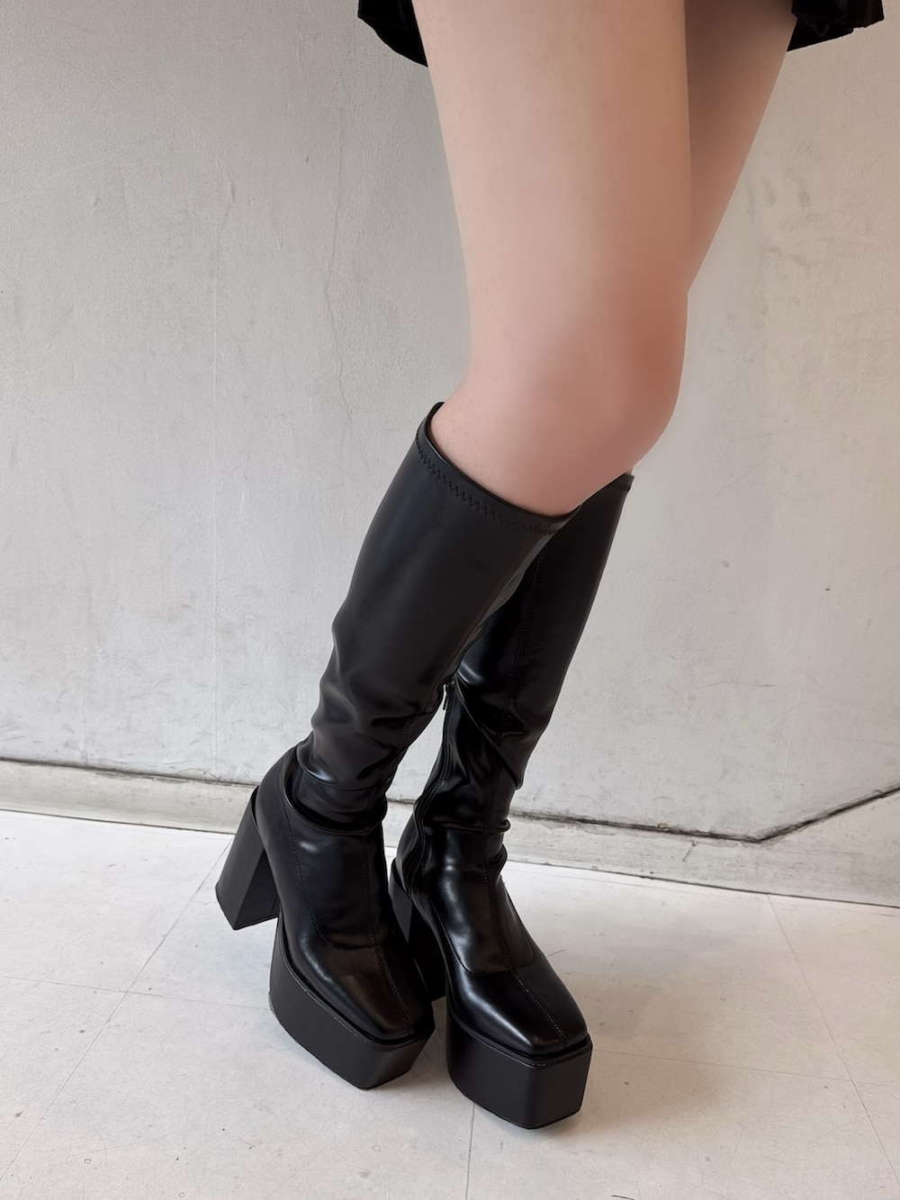 グレー系のパーカー、ブラック系のスカート、ブラック系のブーツを着用したレディースの冬コーディネートの4枚目の写真