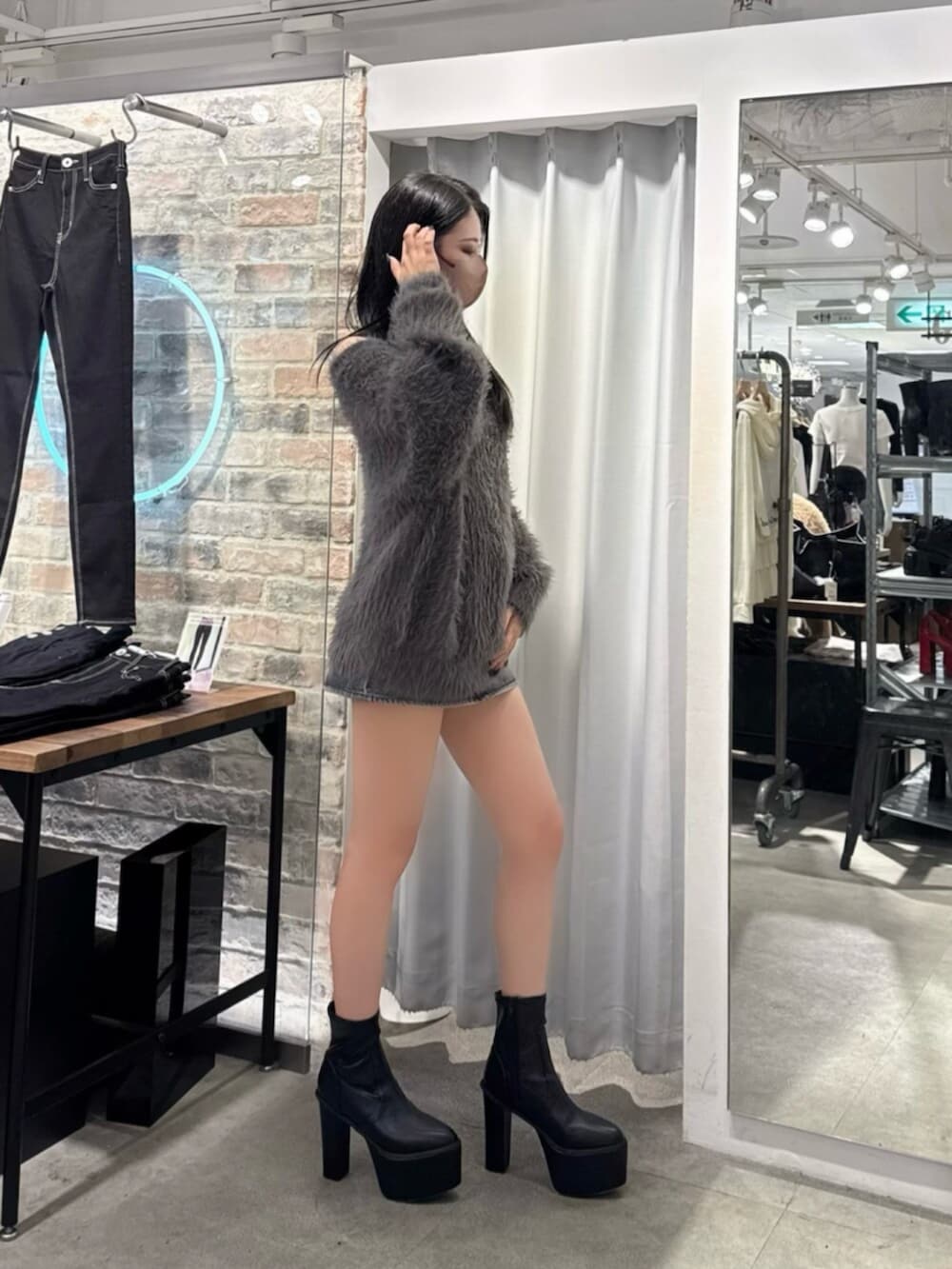 ブラック系のデニムスカート、ブラック系のブーツ、グレー系のニット/セーターを着用したレディースの秋コーディネートの2枚目の写真