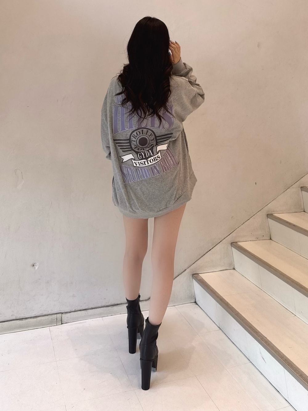 グレー系のスウェット、ブラック系のデニムスカート、ブラック系のブーツを着用したレディースの夏コーディネートの3枚目の写真