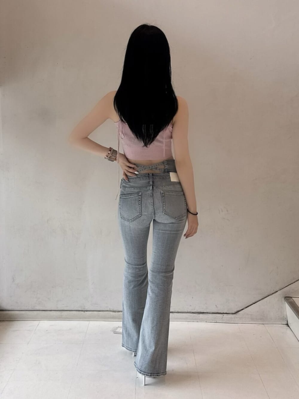ホワイト系のパンプス、ピンク系のキャミソール、ブルー系のデニムパンツを着用したレディースの春コーディネートの2枚目の写真