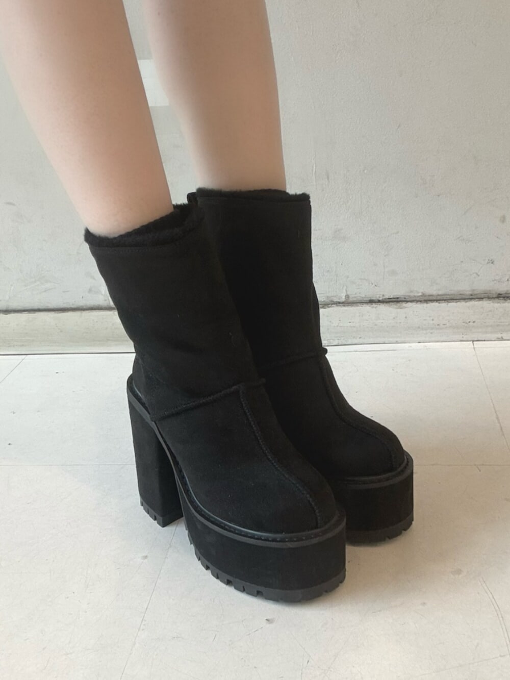 ブラック系のデニムスカート、ホワイト系のニット/セーター、ブラック系のブーツを着用したレディースの冬コーディネートの5枚目の写真