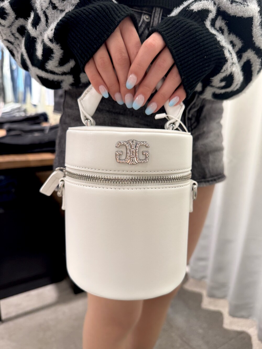 ブラック系のニット/セーター、ブラック系のデニムスカート、ホワイト系のハンドバッグを着用したレディースの冬コーディネートの7枚目の写真