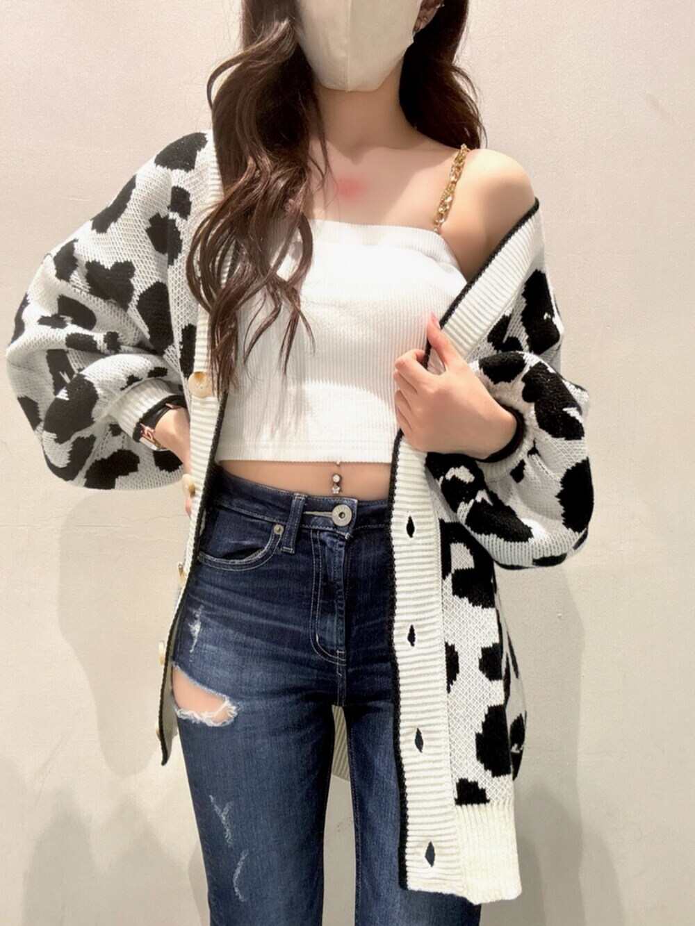 ホワイト系のカーディガン/ボレロ、ホワイト系のキャミソール、ブルー系のデニムパンツを着用したレディースの春コーディネートの4枚目の写真