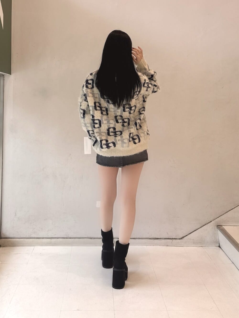 ブラック系のデニムスカート、ホワイト系のニット/セーター、ブラック系のブーツを着用したレディースの冬コーディネートの3枚目の写真