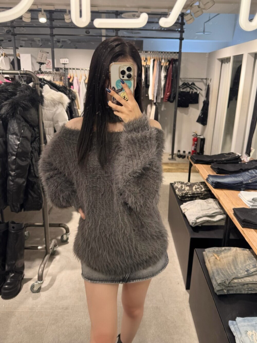 ブラック系のデニムスカート、ブラック系のブーツ、グレー系のニット/セーターを着用したレディースの秋コーディネートの4枚目の写真